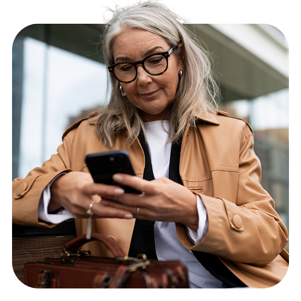Mujer mayor sonriendo mientras revisa su teléfono celular